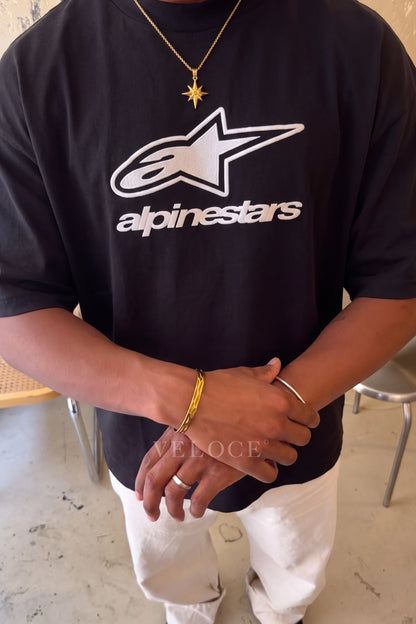 Close-up of the white Alpinestars logo print on the black T-Shirt