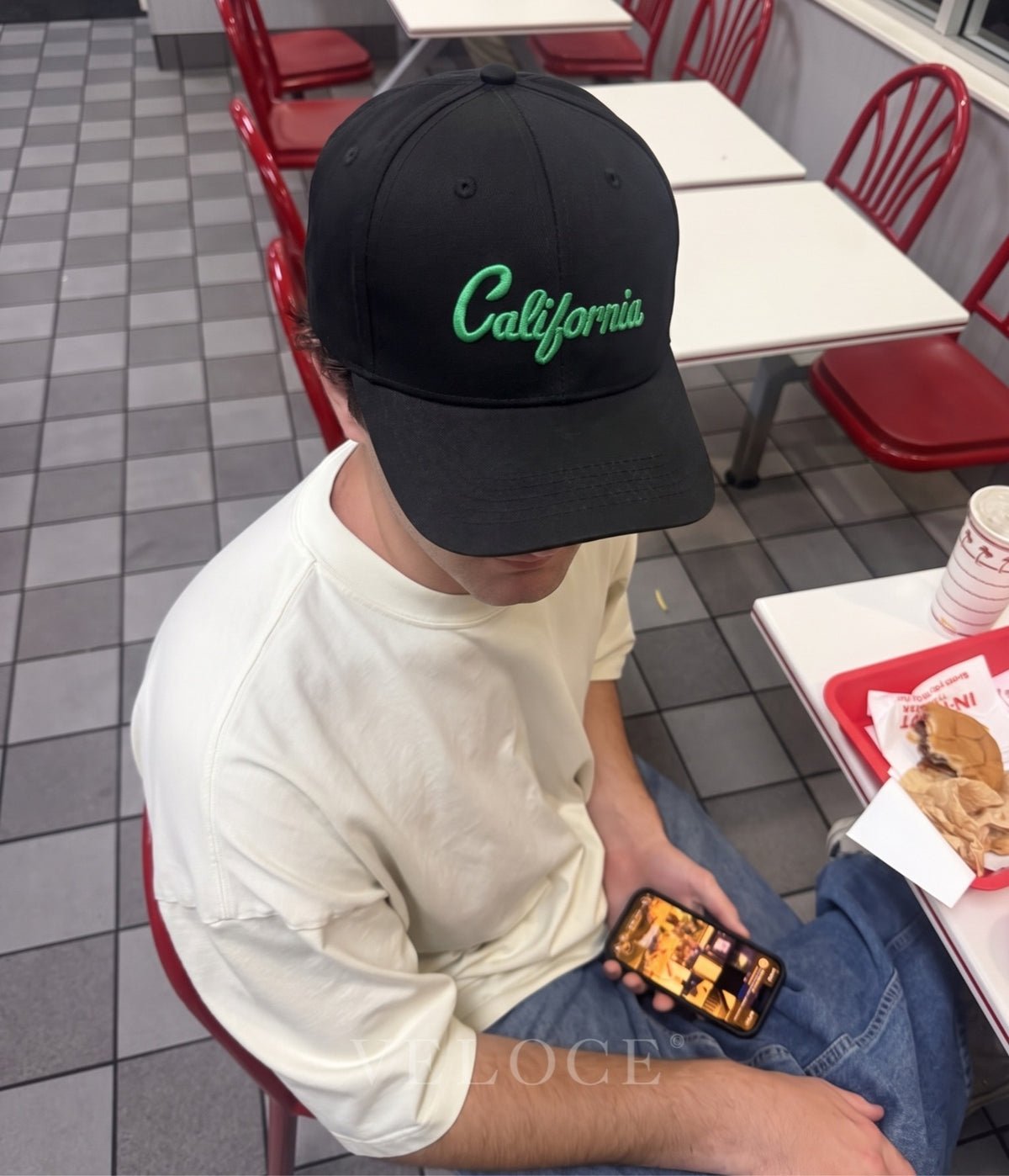 Man wearing the black California embroidered cap with green script