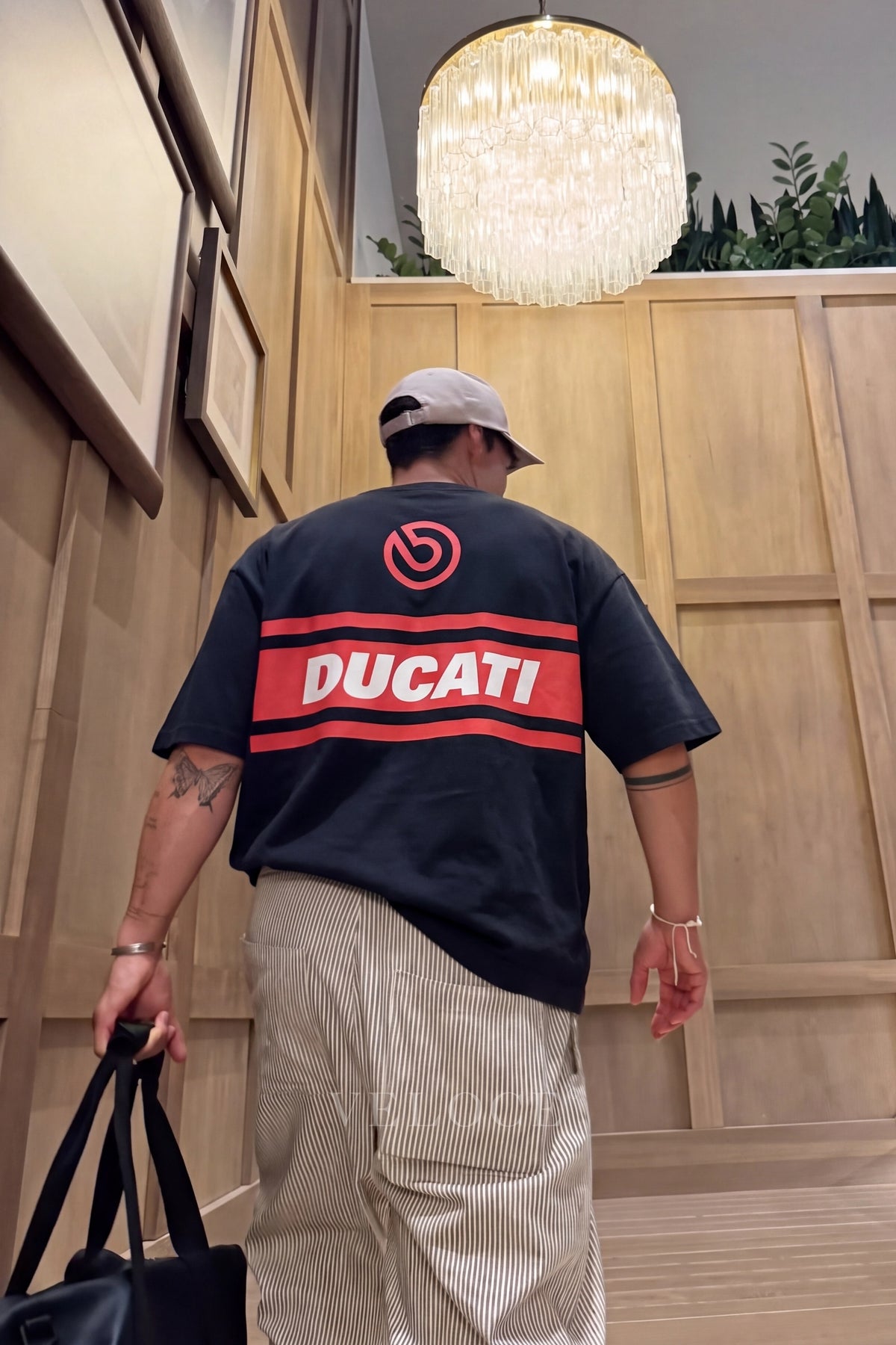 Man in a cap wearing the Ducati Racing T-Shirt indoors, showing the Brembo roundel and Ducati back stripe