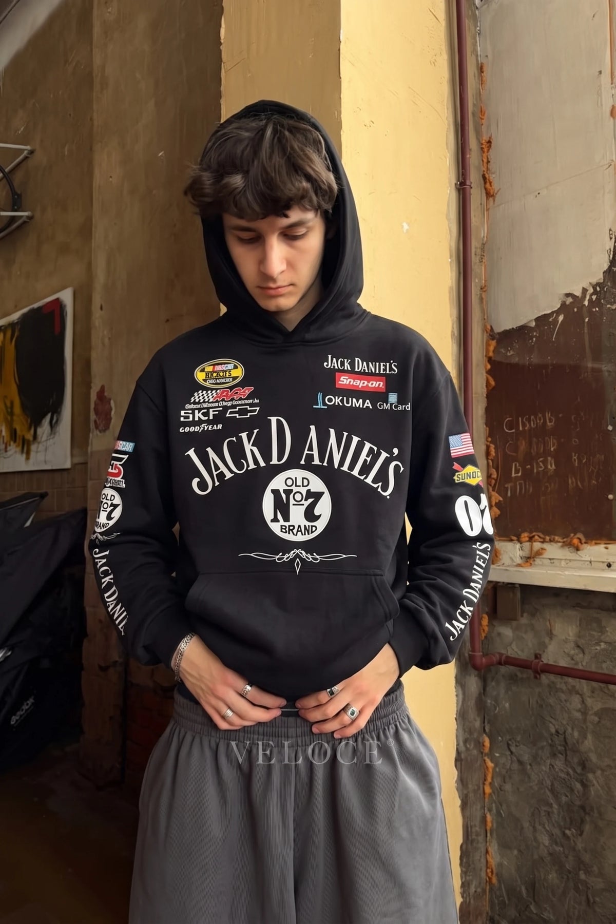 Jack Daniel’s embroidered hoodie worn with the hood up against a painted wall