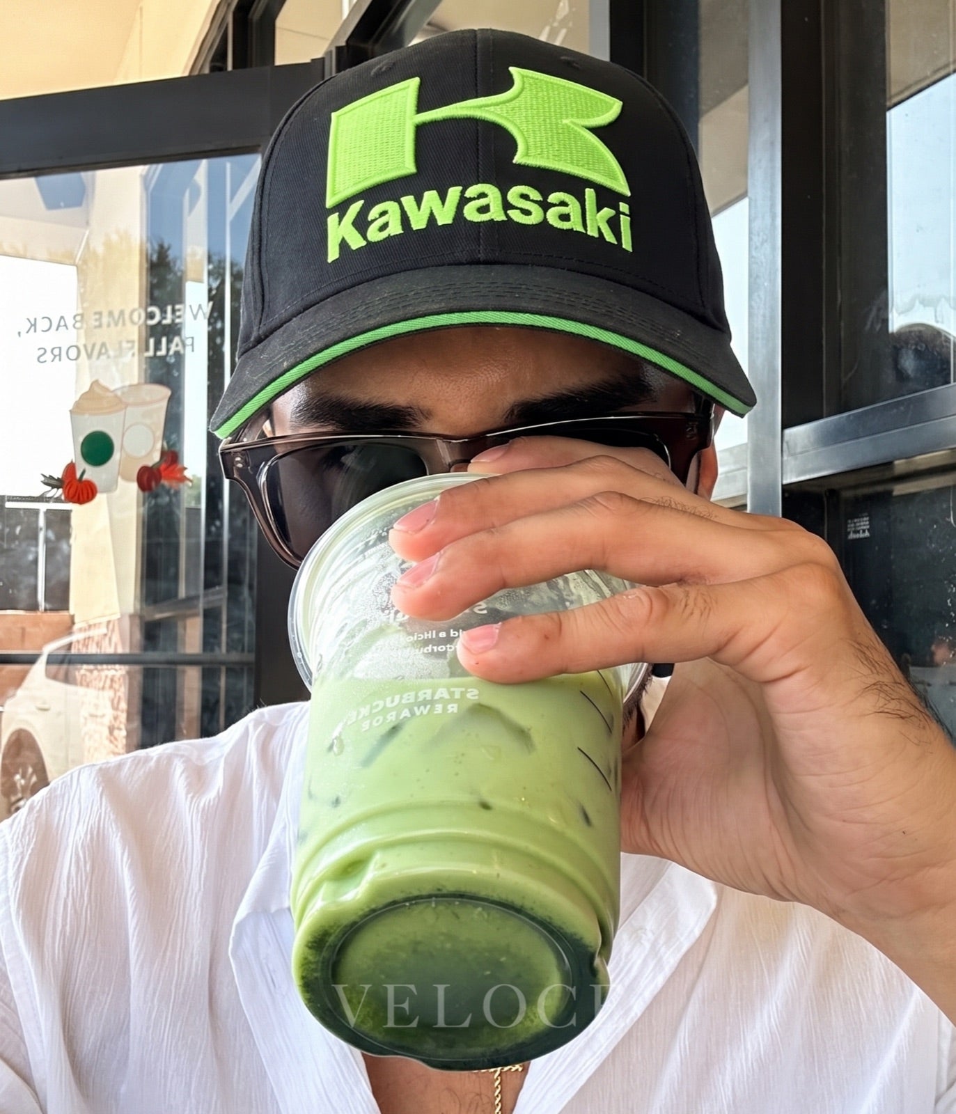 Man wearing the Kawasaki Racing embroidered cap holding an iced matcha