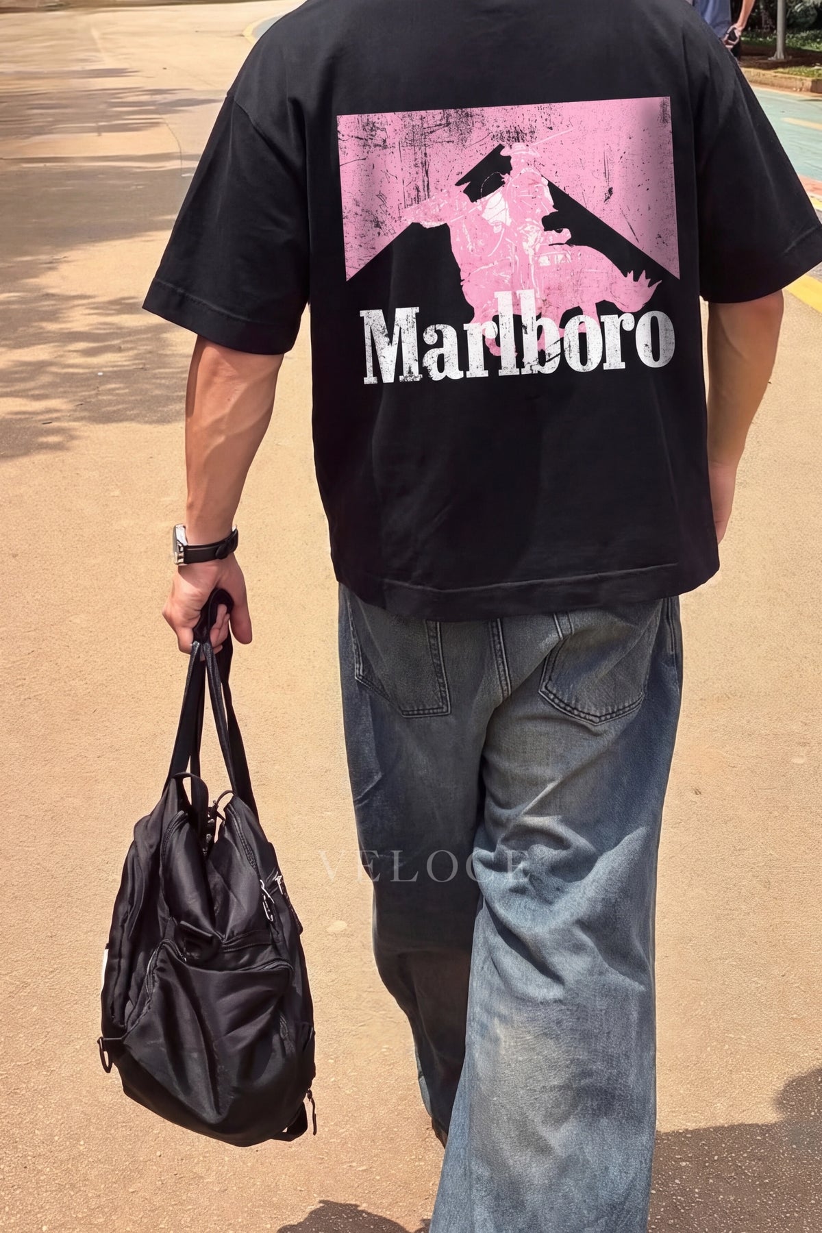 Man walking outdoors wearing the Marlboro Racing T-Shirt with the pink Marlboro Man back print