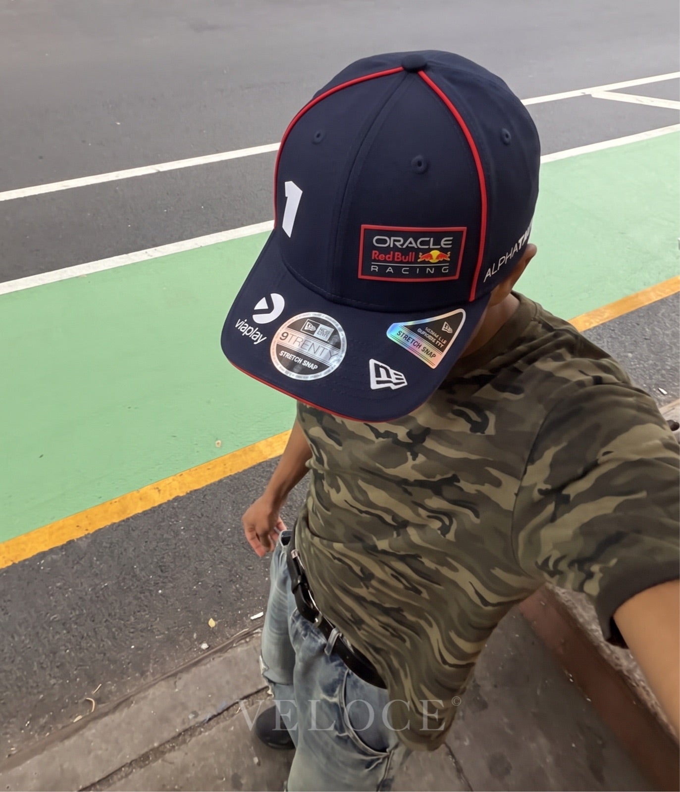 Man wearing the Red Bull F1 Max Verstappen 2023 embroidered cap on a street circuit kerb