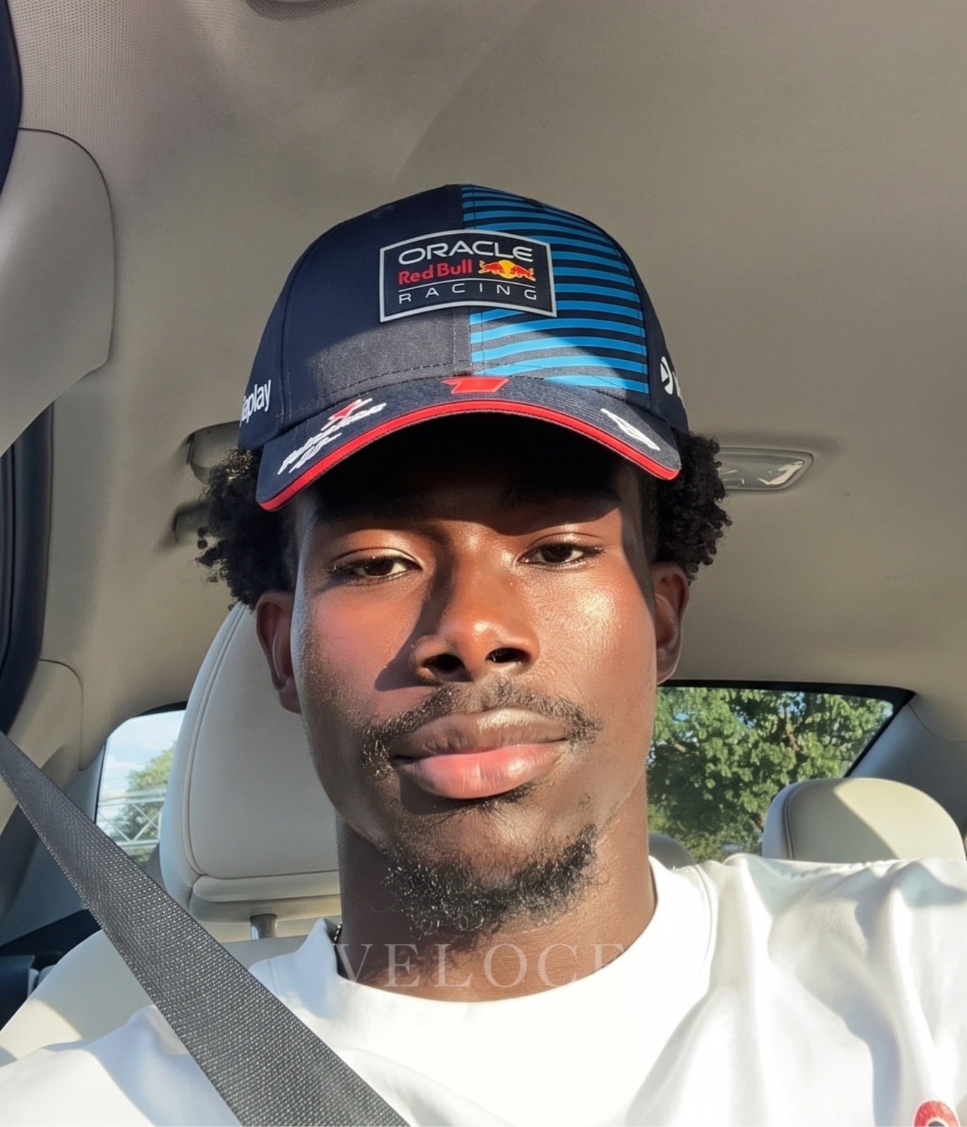 Man wearing the Red Bull F1 Max Verstappen 2024 embroidered cap in a car