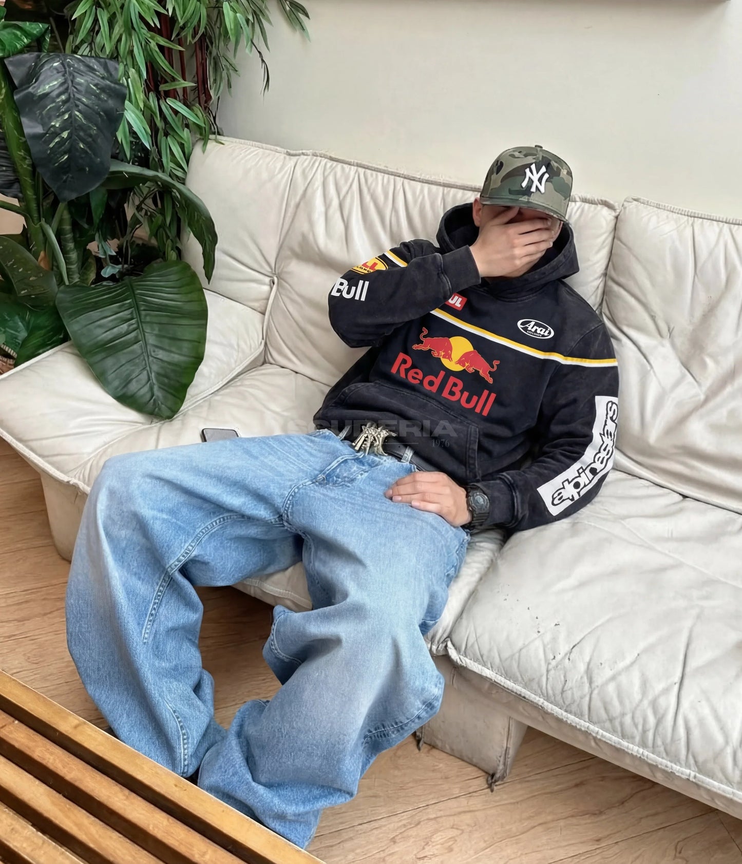 Red Bull Racing Hoodie black washed lifestyle man – vintage oversized motorsport sweatshirt with Red Bull chest logo styled relaxed on sofa with baggy jeans and camo cap