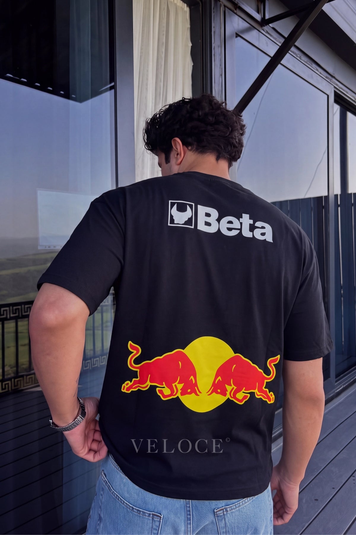 Man on a terrace wearing the classic Red Bull Racing T-Shirt with the Beta back print