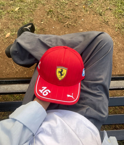 Top-down view of the red Scuderia Ferrari F1 Leclerc embroidered cap worn on a park bench